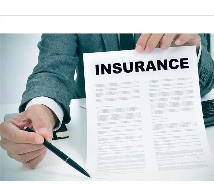 Man holding a paper with a pen, paper says insurance